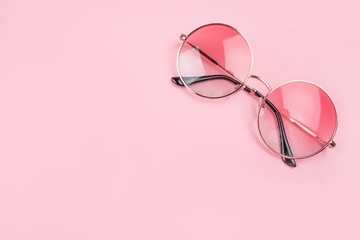 Round gradient sunglasses isolated on pink background.