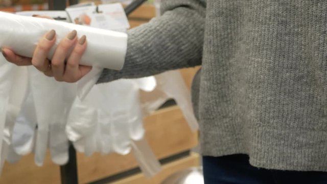woman tears off cellophane plastic bags in the bread department store supermarket.