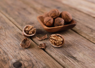 Fototapeta na wymiar walnuts on a rustic wooden table - close up - walnuts broken up and closed