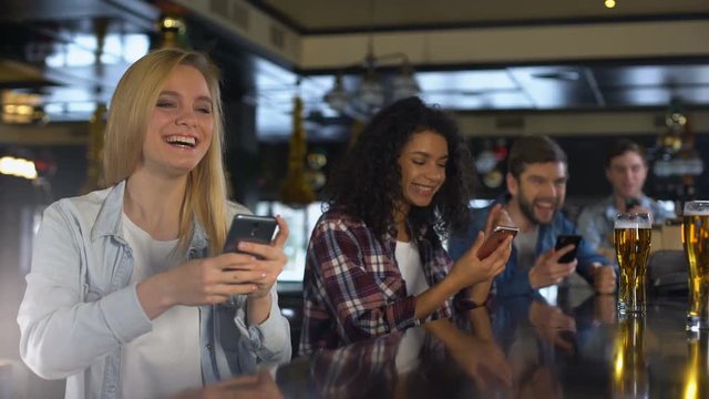 Young people in bar celebrating win in sports betting, bookmaker mobile app