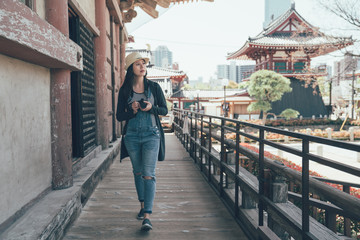 Asia summer holidays asian woman tourist looking at shitennoji temple. female traveler take pictures with DSLR camera. female traveler walking in corridor of shinto travel in old city osaka japan.