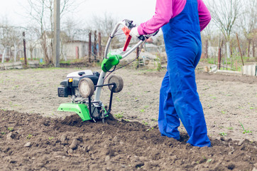 Young girl working in a spring garden with a cultivator