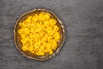 Lot of whole raw pasta funghetto variety in old iron bowl flatlay on grey stone