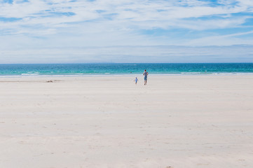 Fototapeta na wymiar Father and son running towards the Atlantic Ocean on the beach in Finistere France