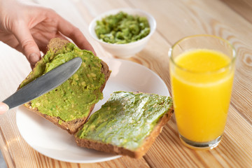 Appetizing pasta from avocado and cucumber in a glass bowl. A slice of white bread is smeared with a delicious green snack from avocado.
