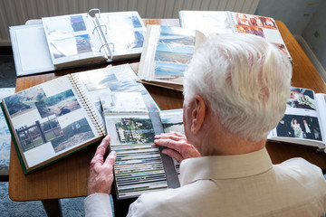 Top view of a senior man looking through old photo albums themes of memories nostalgia photos...