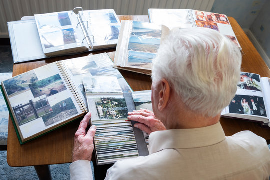 Top view of a senior man looking through old photo albums themes of memories nostalgia photos retired
