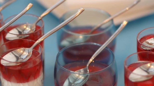 Tasty red and white jelly in glasses with spoons