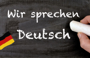 Hand writing Wir sprechen Deutsch translate we are speaking german on a blackboard