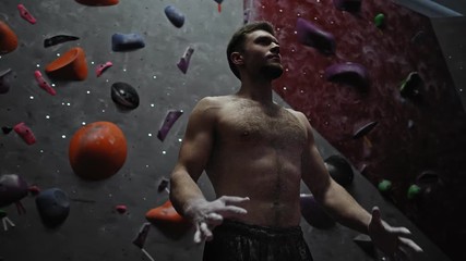 Athletic man applying magnesium before climb in a bouldering gym