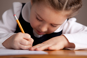 Little Girl Writing While Sitting in Old School Desk - Education - Closeup