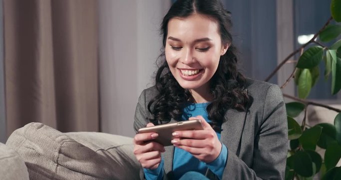 Happy businesswoman playing online game on mobile phone at home