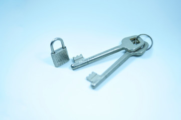 A little padlock with too large keys on white surface.