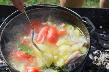 Shurpa soup in cast-iron cauldron outdoor. Food for hike.