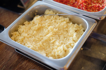 Sliced garlic on a silver aluminum bowl.