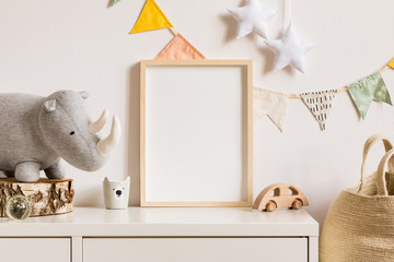 The modern scandinavian newborn baby room with mock up photo frame, wooden car, plush rhino and clouds. Hanging cotton flags and white stars. Minimalistic and cozy interior with white walls.Real photo - obrazy, fototapety, plakaty