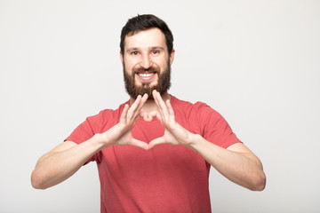 Close-up portrait of his he nice attractive handsome cheerful positive bearded man wearing checked t-shirt showing heart shape boyfriend 14 february isolated over beige pastel background