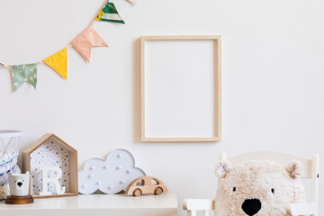 Stylish scandinavian child room with mock up photo poster frame on the white wall. Cute modern...