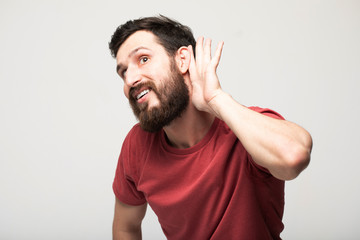 bearded man, listening, viewing the gesture of hand behind the ear, isolated on grey background