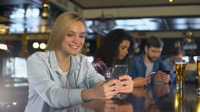 Young people using cellphones in bar, reading messages in dating app, free wi-fi
