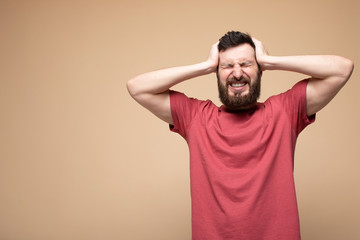Obraz premium Portrait of young man suffering from severe headache, pressing fingers to temples, closing eyes to relieve pain with helpless face expression