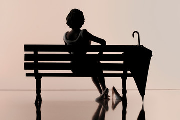 woman from behind sitting on a bench with closed umbrella