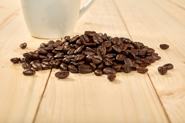 Coffee beans with coffee cup isolated on wooden table