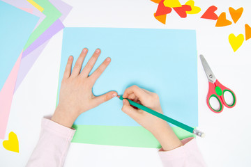 How to make paper bunny for Easter greetings and fun. Children art project. DIY concept. Kids hands makes paper craf. Step by step photo instruction. Step 2. Draw hand outline