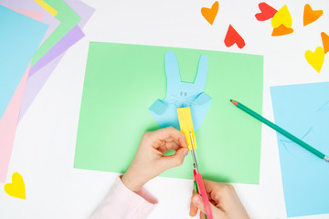 How to make paper bunny for Easter greetings and fun. Children art project. DIY concept. Kids hands makes paper craf. Step by step photo instruction. Step 8. Cut the ears and nose different color.