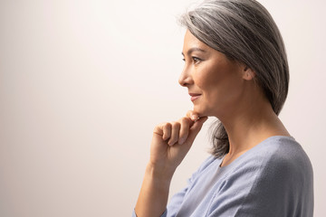Pensive woman is touching chin and slightly smiles