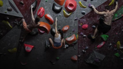 Athletic woman and men practicing in a bouldering gym