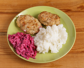 Cutlets, boiled rice and chopped beets on a plate on the table.