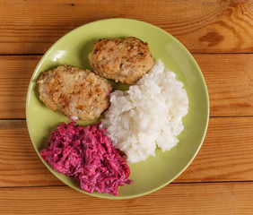 Cutlets, boiled rice and chopped beets on a plate on the table.