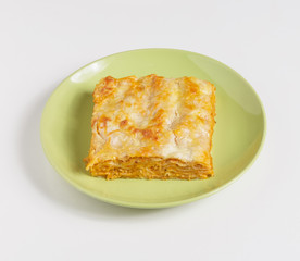 A piece of lasagna on a plate on a white background.
