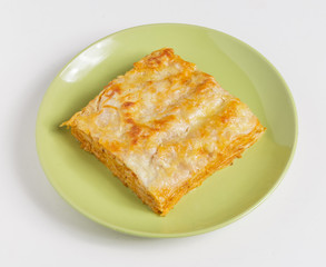 A piece of lasagna on a plate on a white background.