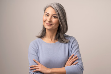 Smiling Asian senior woman with crossed arms - Powered by Adobe