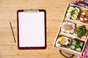 Stylish and tasty composition of vegan and vegetarian breakfast. Planning your healthy diet. Organic vegetables and sandwiches on the wooden table. Mock up menu concept. Fresh and healthy meal. 
