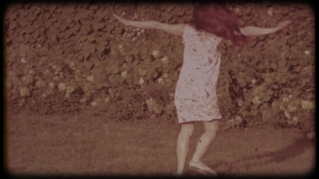 Family video archive. Retro camera 8&nbsp;mm. Old film. Young attractive woman having fun in the green garden. Portrait of a smiling brunette with dimpled cheeks against a green park. Pretty girl in summer