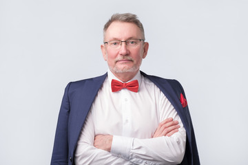 Senior man wearing eyeglasses aand blue suit smiling warmly and confident.