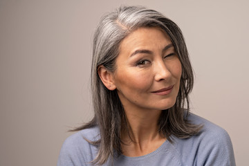 Charming Asian mature woman smiles at camera