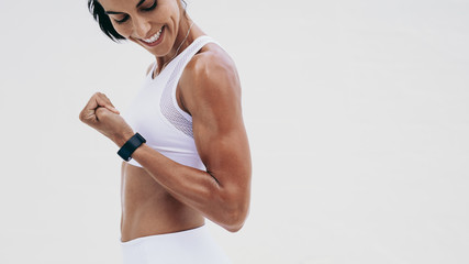 Close up of a smiling fitness woman looking at her hand - obrazy, fototapety, plakaty