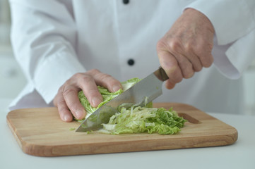 Portrait of chef male hands cooking salad close up