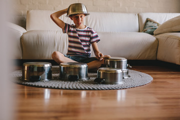 Future drummer boy with cooking pots at home