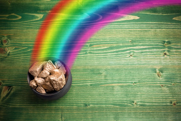 Pot Of Gold on green woden background. Magical Treasure with Rainbow