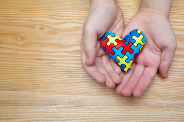World Autism Awareness day, puzzle or jigsaw pattern on heart with autistic child's hands