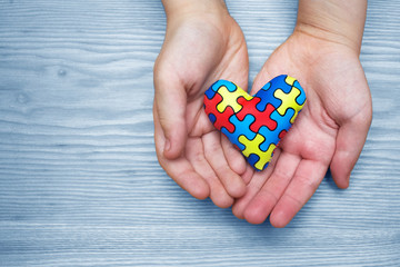 World Autism Awareness day, puzzle or jigsaw pattern on heart with autistic child's hands