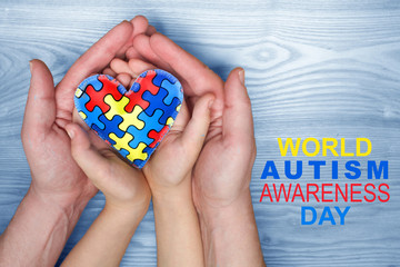 World Autism Awareness day, puzzle or jigsaw pattern on heart with autistic child's and father hands