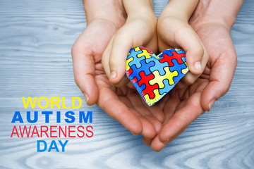 World Autism Awareness day, puzzle or jigsaw pattern on heart with autistic child's and father hands