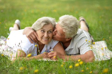 Portrait of happy senior couple lying in summer park