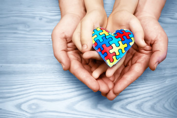 World Autism Awareness day, puzzle or jigsaw pattern on heart with autistic child's and father hands